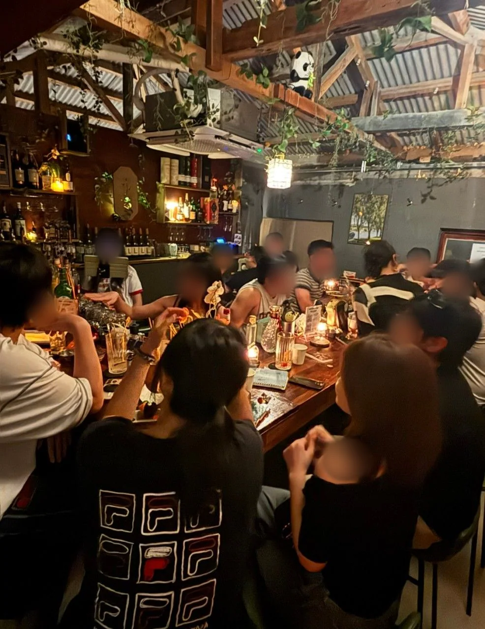 つる草が垂れる梁の見える天井の下、バーカウンターを囲んで座るお客様